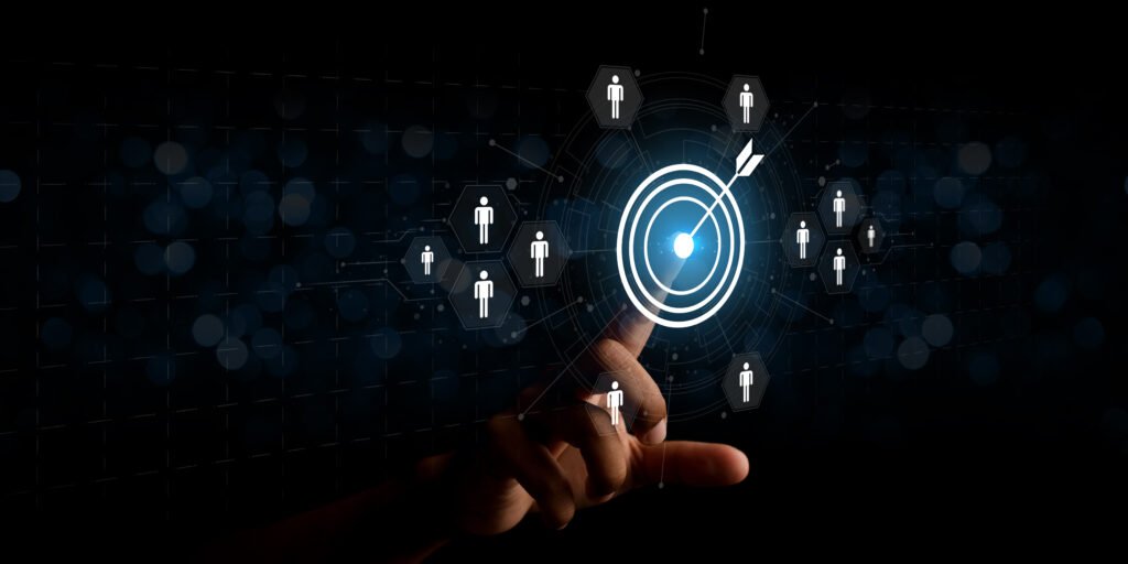 Mão apontando para um alvo digital iluminado cercado por ícones de pessoas, representando a identificação e segmentação do público-alvo em estratégias de marketing.