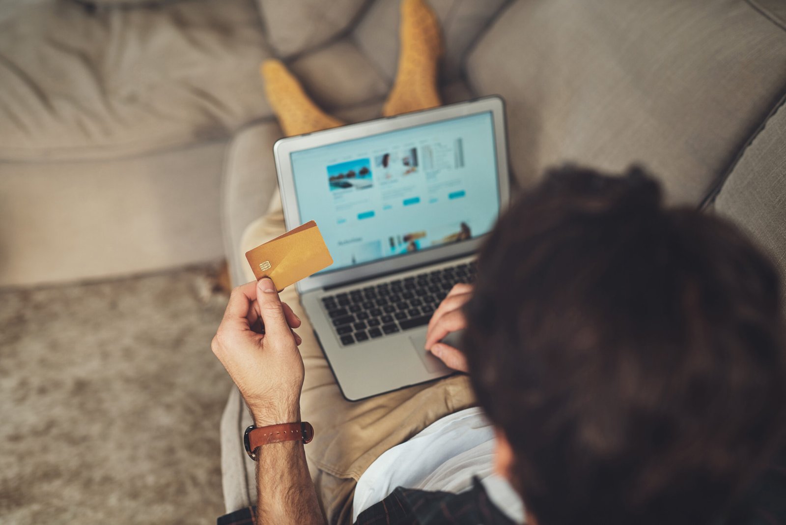 Pessoa utilizando um notebook para realizar compras online enquanto segura um cartão de crédito. A cena representa o comportamento do consumidor digital, decisões de compra e o crescimento do comércio eletrônico.