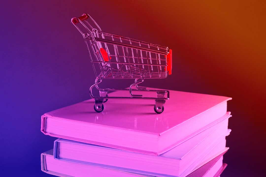 carrinho de compras em miniatura, em cima de vários livros remetendo ao conceito de playbook de vendas