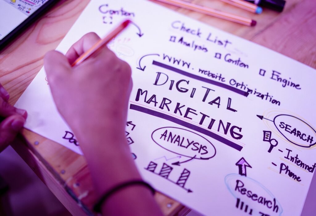 Person writing a digital marketing strategy on a planning sheet with SEO, content, analysis, search, and research concepts illustrated in a brainstorming diagram.