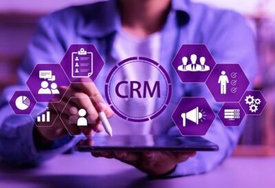 Professional using a tablet with a CRM dashboard displaying customer management, sales, marketing automation, and business analytics tools.