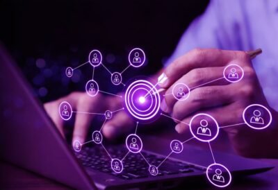 Professional using a laptop while analyzing a digital network of customer connections centered around a target, representing lead generation and audience targeting strategies.