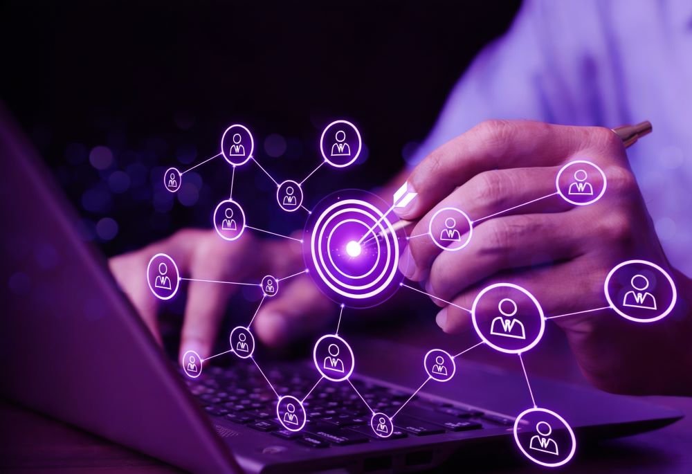 Professional using a laptop while analyzing a digital network of customer connections centered around a target, representing lead generation and audience targeting strategies.